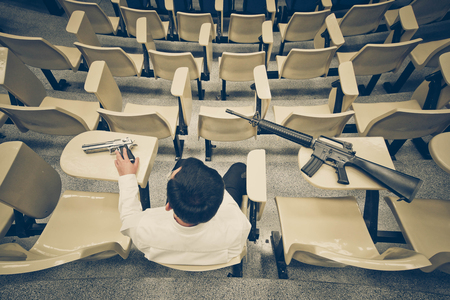 A man with a pistol and a rifle in a lecture room / Armed campus conceptの写真素材