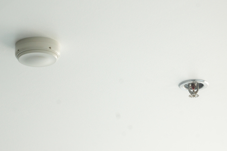 Fire detector and extinguisher with gray ceiling as backgroundの写真素材
