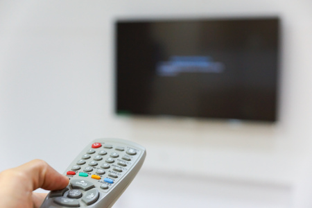 Hand holding a television remote trying to switch it onの写真素材