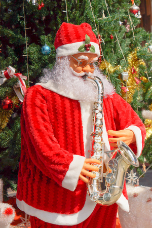 Santa Clause playing trumpet near big Christmas treeの写真素材