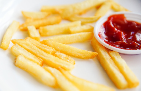 French fries and ketchup on white plate isolated on white