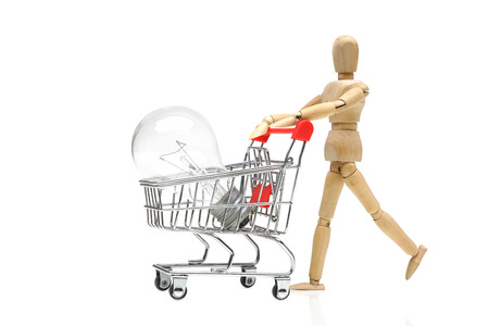Wood Figure Mannequin pushing a shopping card with incandescent light bulb / The concept of selling and buying. Business ideasの写真素材
