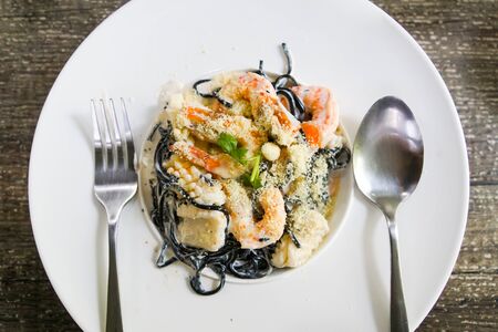 Top view of black spaghetti with shrimps and squid on a white dishの写真素材