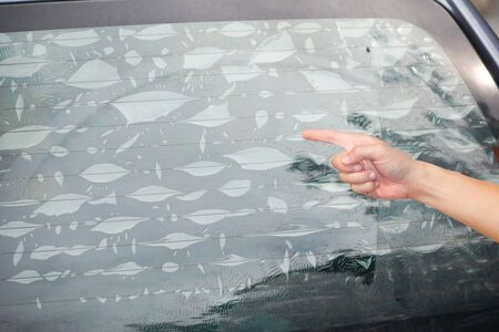 Hand pointing at air bubbles on window film of a carの写真素材