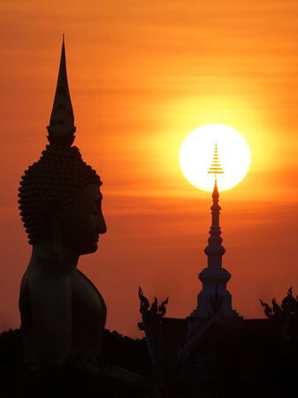 Sunset in front of a buddhist sculptureの写真素材