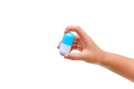 Kid's hand holding a big capsule medicine isolated on white background / Drug overdose on children conceptの写真素材
