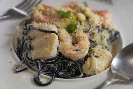 Black spaghetti with shrimps and squid on a white dishの写真素材