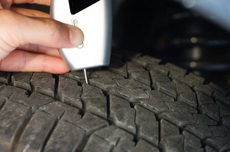 Using a digital tire tread depth measuring tool with old tire  / Road safety and risks of using old tire conceptの写真素材