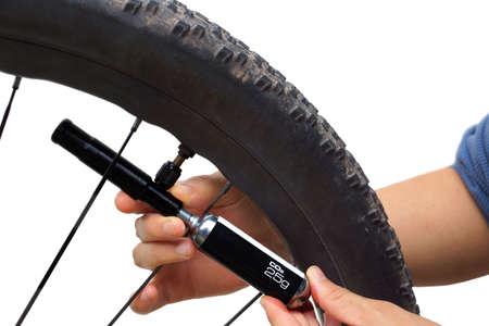 A cyclist using a tool to pump CO2 into a flat tire isolated on white backgroundの写真素材