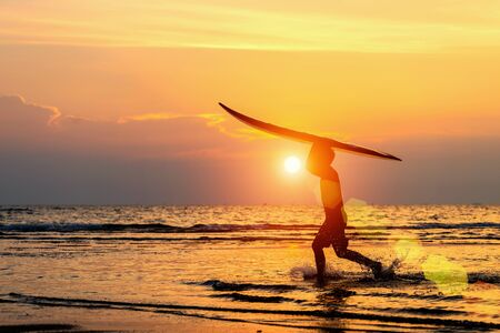 A surfer with his surfboard at the dunes looking to the wavesの写真素材