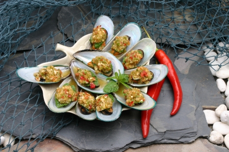 Baked mussels topped with seafood sauceの写真素材