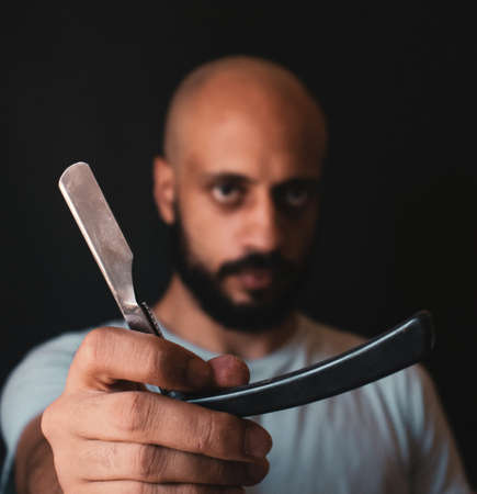 Bald bearded man holding barber's straight razor forwardの写真素材