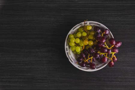 bowl full of green and red grapes with black backgroundの写真素材
