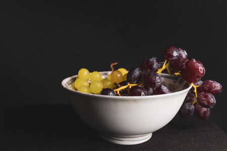 bowl full of green and red grapes with black backgroundの写真素材