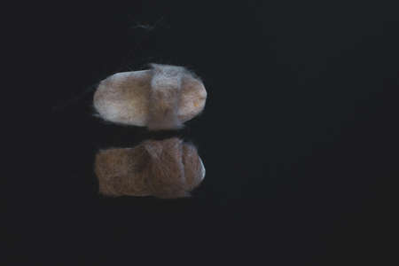 tiny slippers made out of cat hair isolated on black background