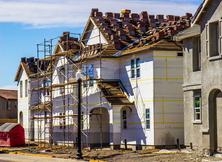 New Construction Of Two Story Homes With Scaffolding & Roofing Materials