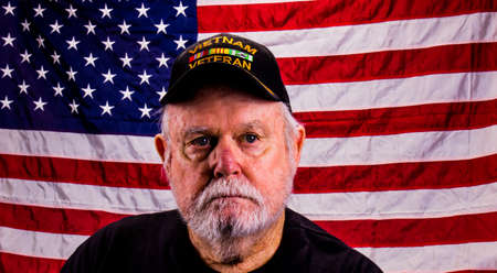 Old Vietnam Veteran Looking Away From Camera With American Flag Background