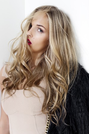 Awesome beautiful smiling blonde woman in black fur coat stylish evening elegant dress posing on white isolated backgroundの写真素材