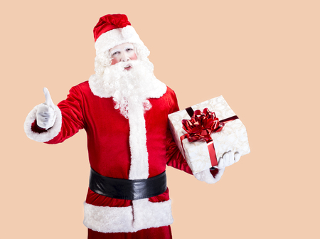 Funny Santa Claus with gift standing in front of color backgroundの写真素材