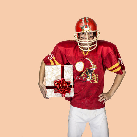 American football player in red uniform posing with big giftの写真素材