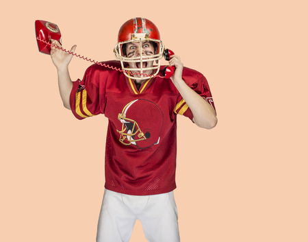 American football player in red uniform posing on color backgroundの写真素材