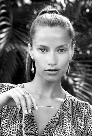Portrait of beautiful fashion woman in tropics with black sunglasses. Sexy girl wearing color overalls, stylish earrings and ring posesの写真素材
