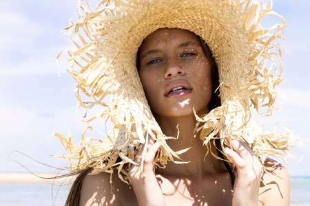 Hot beautiful woman in sunhat and bikini standing with her arms raised up enjoying looking view of beach ocean on hot summer day. Vacation.Photo from Phuket islandの写真素材