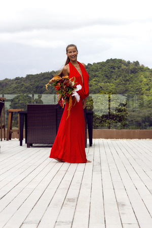 Fashion woman in red dress with flowers posing on tropical sea view. New year ball. Phuket , Thailandの写真素材