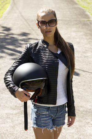 Beautiful woman in black leather jacket with helmet on road. Phuket, Thailandの写真素材