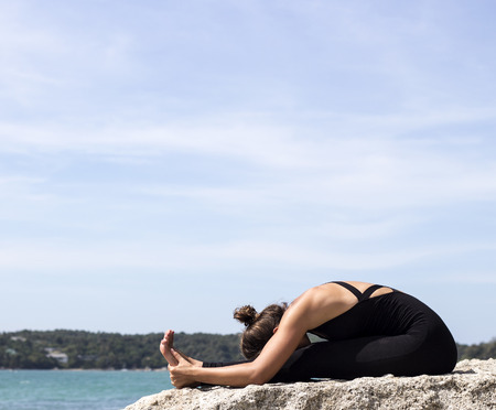 Yoga woman poses on beach near sea and rocks. Phuket, Thailandの写真素材