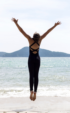 Yoga woman poses on beach near sea and rocks. Phuket, Thailandの写真素材