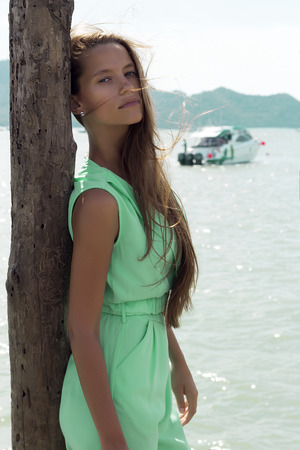 Beautiful tanned woman on pier in stylish elegant clothes poses enjoying amazing view. Fashion look. Phuket, Thailandの写真素材