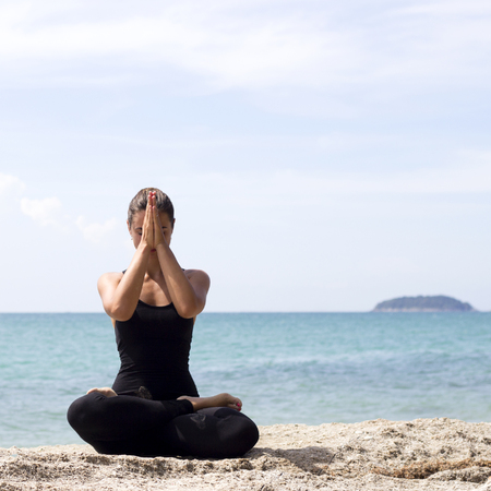 Yoga woman poses on beach near sea and rocks. Phuket, Thailandの写真素材