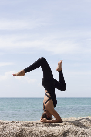 Yoga woman poses on beach near sea and rocks. Phuket, Thailandの写真素材