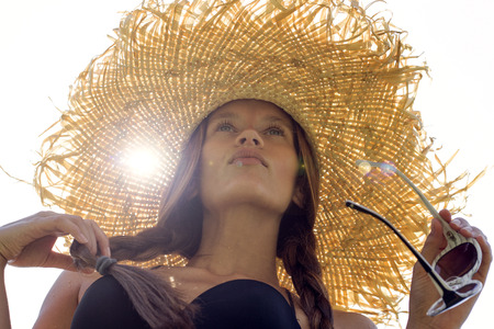 Woman in sunglasses and hat black stylish swimsuit with pigtails poses on roof enjoying landscape view. Phuket, Thailand. High fashion look.の写真素材