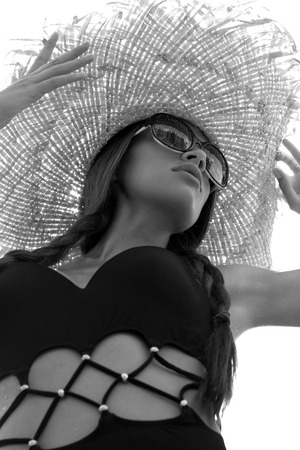 Woman in sunglasses and hat black stylish swimsuit with pigtails poses on roof enjoying landscape view. Phuket, Thailand. High fashion look.の写真素材