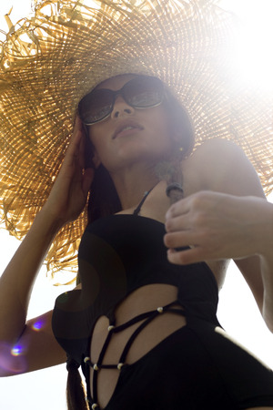Woman in sunglasses and hat black stylish swimsuit with pigtails poses on roof enjoying landscape view. Phuket, Thailand. High fashion look.の写真素材