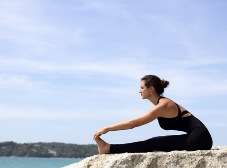Yoga woman poses on beach near sea and rocks. Phuket, Thailandの写真素材