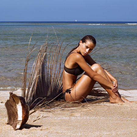 Woman in bikini with palm branch on beach near sea enjoying sun. Long wet hair. Volume curly hairstyle. Tropics. Hot summer day. Sexy girl. Vacation. Photo from Phuket island.の写真素材
