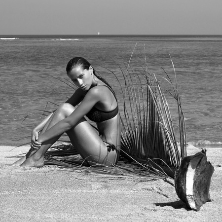 Woman in bikini with palm branch on beach near sea enjoying sun. Long wet hair. Volume curly hairstyle. Tropics. Hot summer day. Sexy girl. Vacation. Photo from Phuket island.の写真素材