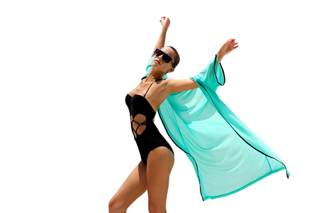 Dancing woman in black swimsuit sunglasses and turquoise beach dress poses on white isolated background. High fashion look.  Hair upの写真素材