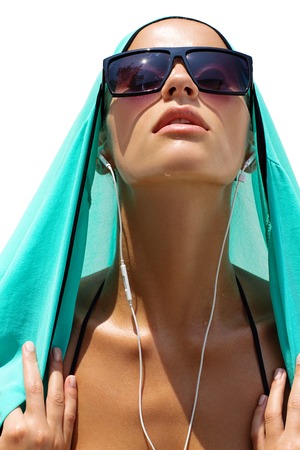 Dancing woman with headphones in black swimsuit and sunglasses poses on white isolated background. High fashion look.の写真素材