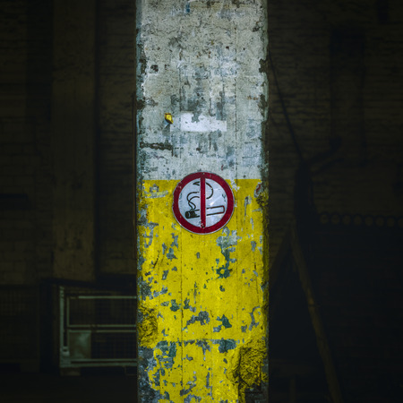 No smoking sign on old, damaged industrial building column painted in cigarette colorsの写真素材