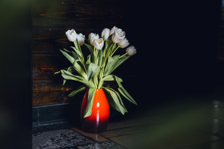 Flowers in a red vase and a dark backdropの写真素材