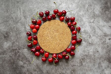 Background image , marble countertop ,cork stand for hot, and cherry berries. Summer season,harvesting berries ,jam,compotes,place for inscriptionsの写真素材
