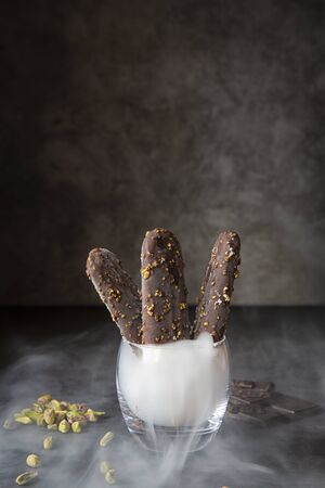 Chocolate ice cream with pistachio nuts on a dark background and with steam .Summer season,hot...