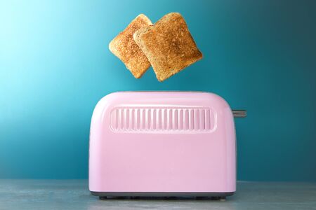 a pink toaster oven with leaping slices of fried bread on a blue backgroundの写真素材
