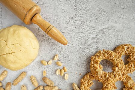 Shortbread cookie dough, rolling pin, peanuts and cookies on the kitchen table.festive cakes.