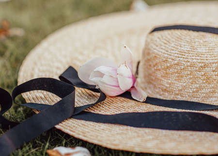 Spring flowering. An open aperture with a slight blur. A womans straw hat with a large brim and a magnolia flower lying on it.の写真素材