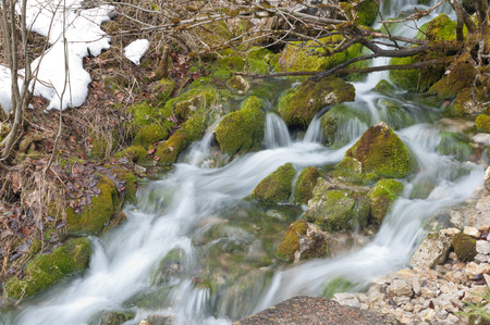 Snow and mossy stones at a cataractの写真素材
